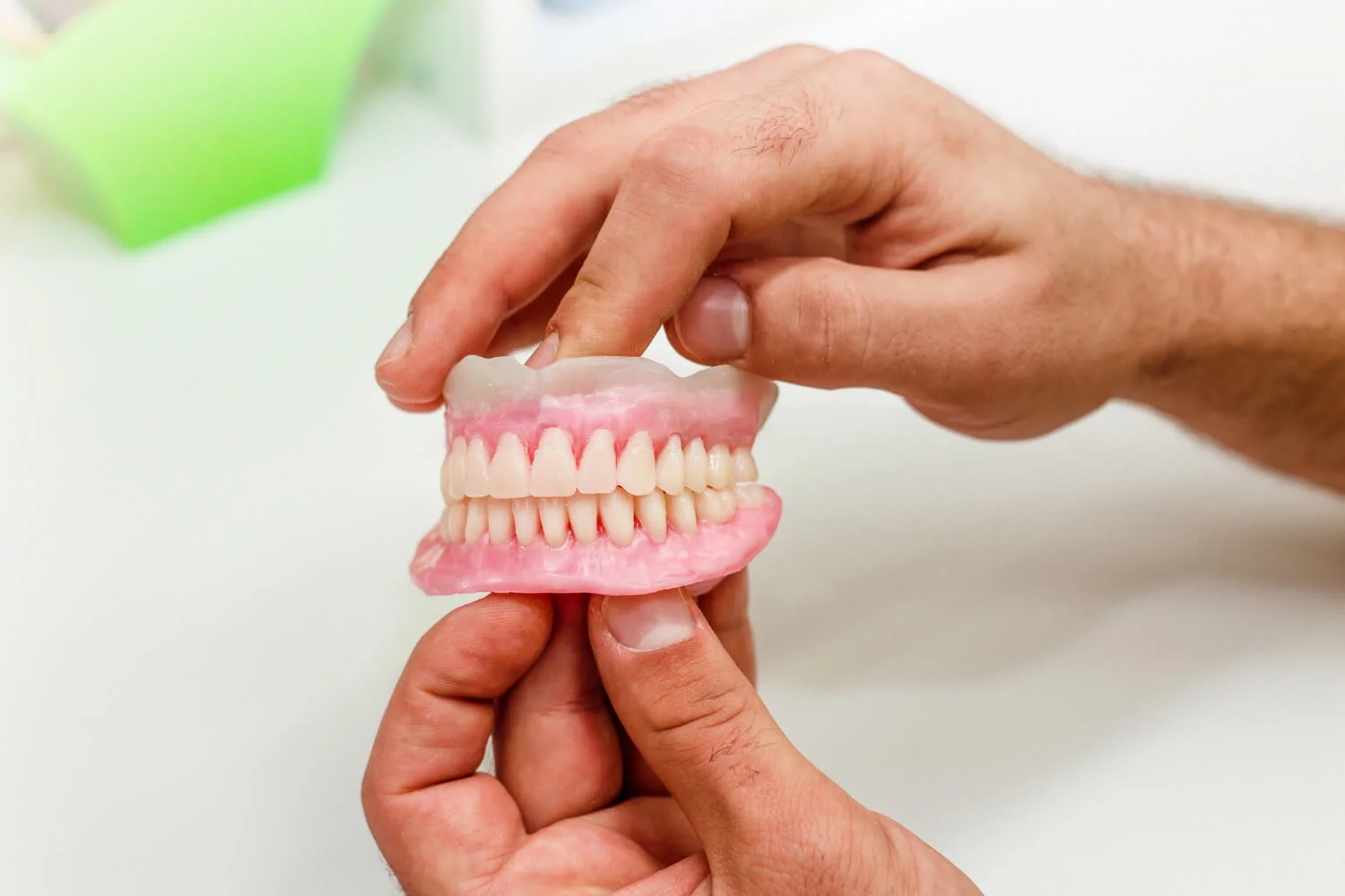 Especialista segurando prótese protocolo sobre implantes, solução de dentes fixos na Felice Odontologia no Anália Franco e Tatuapé.