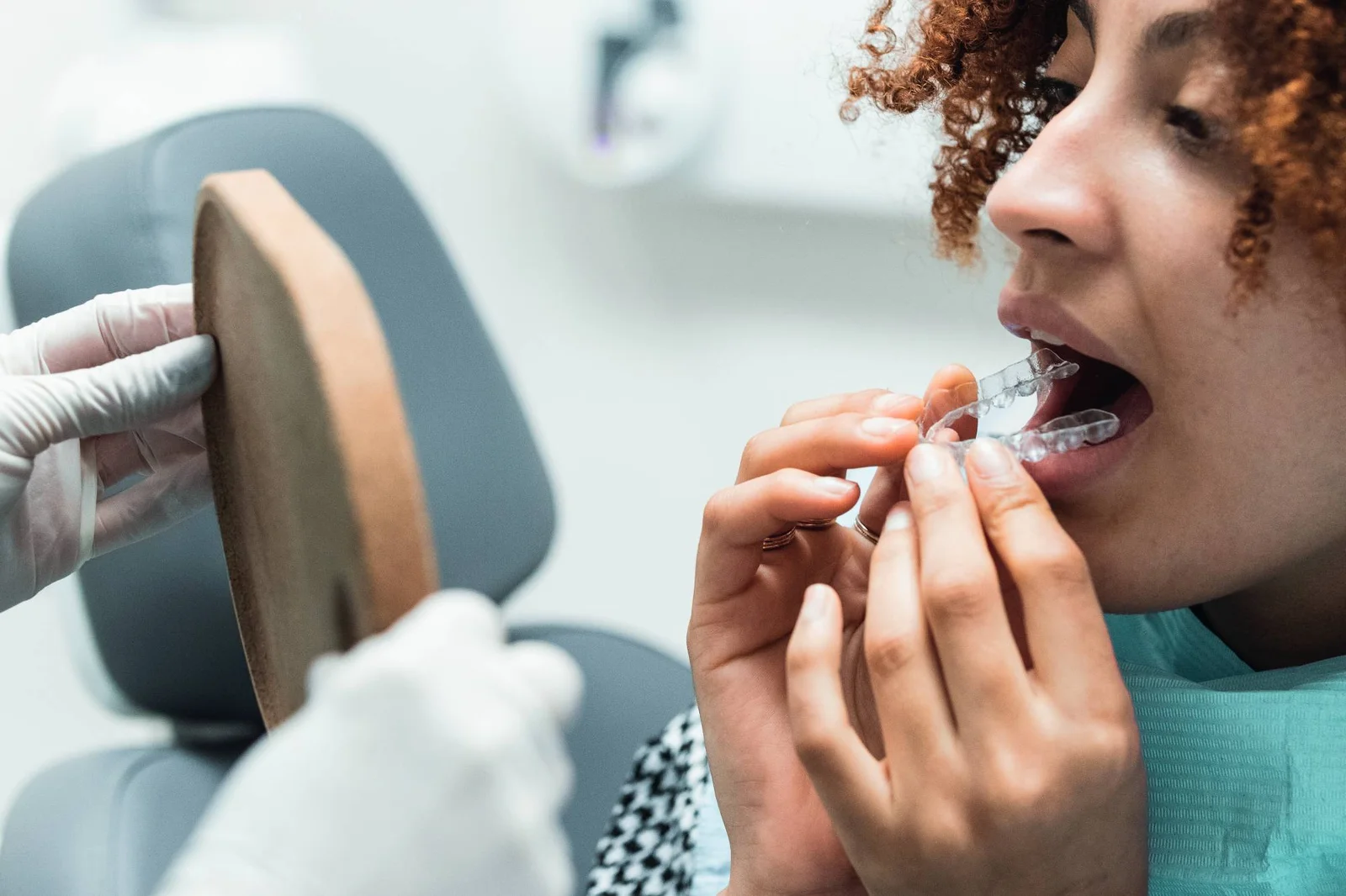 Close-up de paciente sorridente colocando alinhador transparente Invisalign em consultório da Felice Odontologia no Anália Franco.