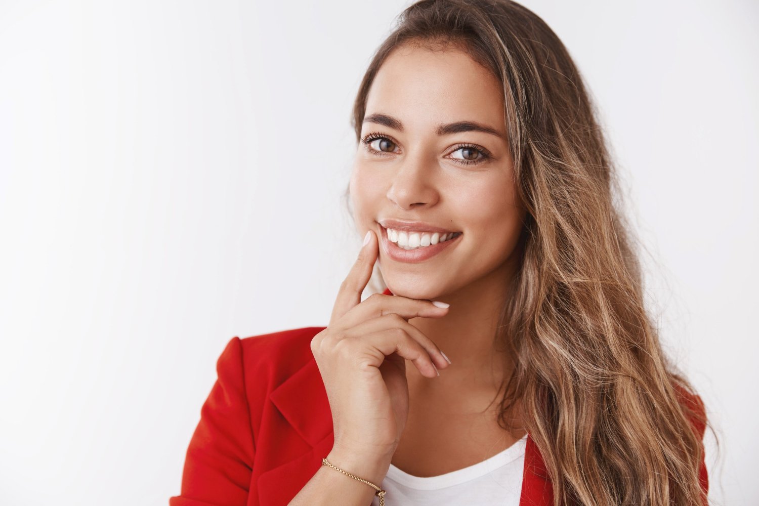 Mulher de blazer vermelho sorri mostrando dentes alinhados com lentes de contato dental na Felice Odontologia no Jardim Anália Franco.