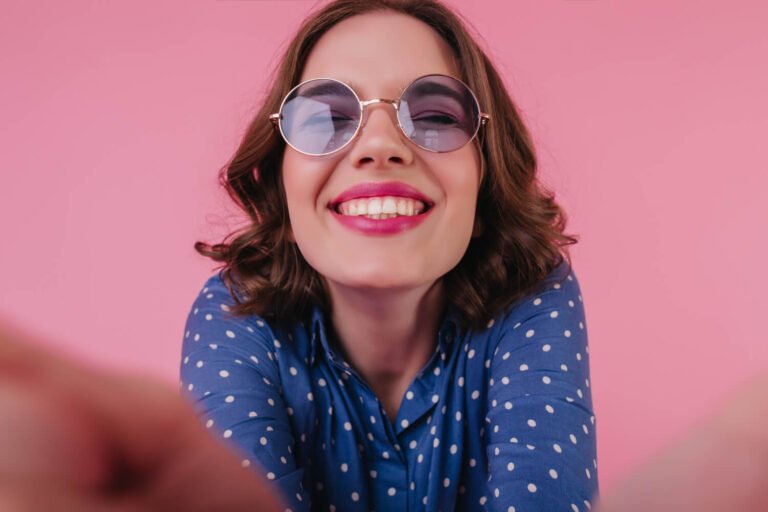 Mulher com óculos escuros sorri mostrando os dentes alinhados com Invisalign na Clínica Felice Odontologia no Jd Anália Franco
