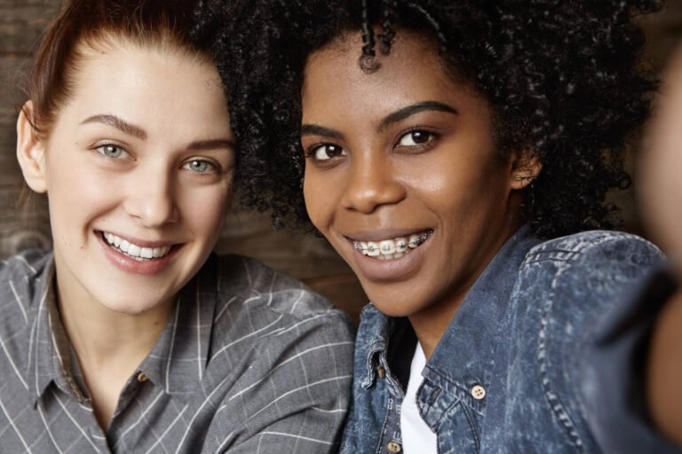 Duas mulheres sorrindo: uma com alinhador invisível e outra com aparelho fixo, em consulta na Felice Odontologia no Jd. Anália Franco.